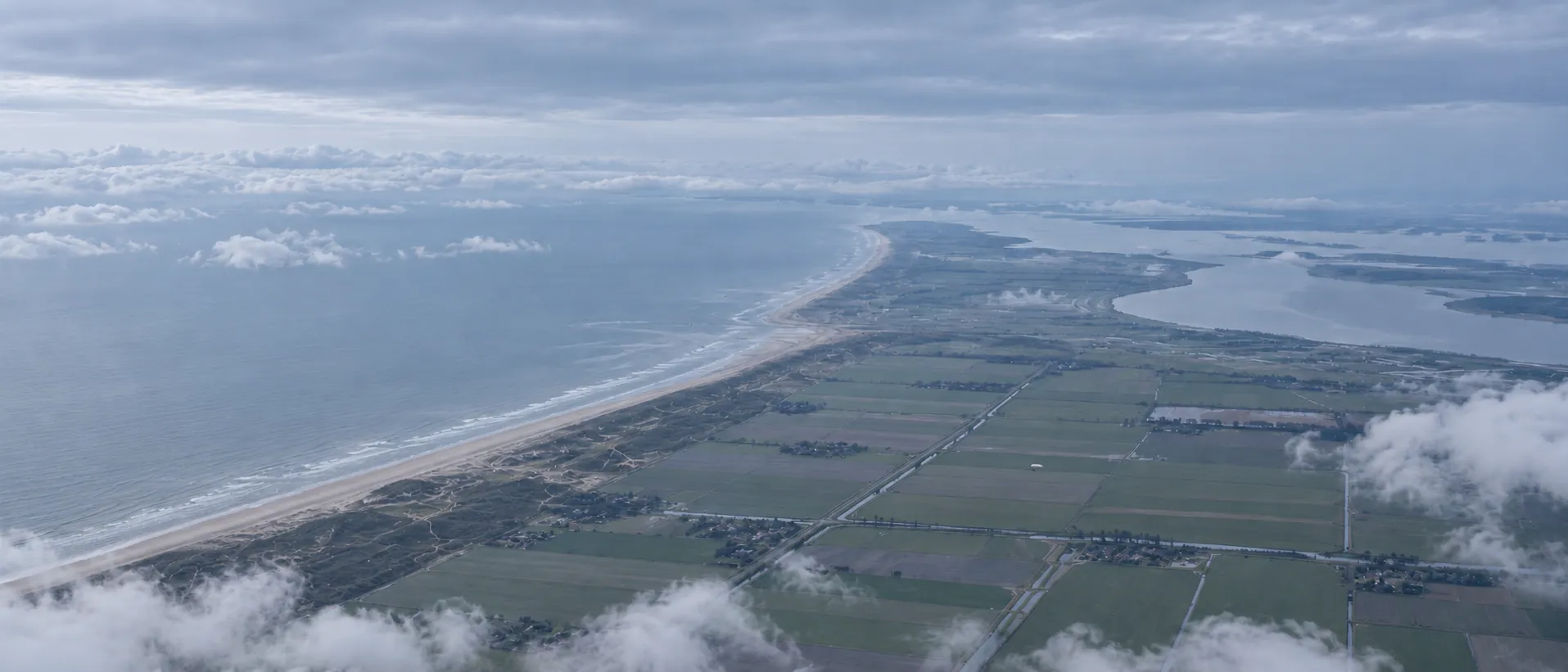High aerial view of the Dutch coast and polders, with the airship far below